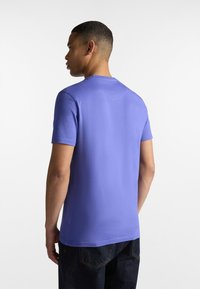 T-shirt da uomo a maniche corte di un vivace colore viola. Realizzato in tessuto morbido, presenta un colletto rotondo e una vestibilità rilassata con una texture liscia.