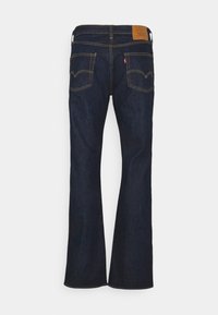 Jean évasé en denim bleu foncé, avec un patch de marque en cuir sur la taille arrière et des coutures jaunes contrastantes. Design classique à cinq poches.