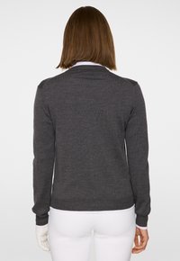 Grå stickad tröja med långa ärmar och rund halsringning. Har ribbade muddar och nederkant. Slät textur, minimalistisk design.