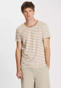 Koszulka z krótkim rękawem w paski w jasnym kremowym kolorze z cienkimi brązowymi paskami. Okrągły dekolt z kontrastującym brązowym wykończeniem. Materiał bawełniany, luźny krój.