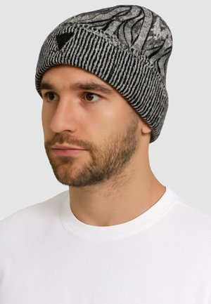 Cappello a maglia grigio con motivi a onde nere, texture a coste nella parte inferiore e dettaglio logo triangolare sulla parte anteriore.