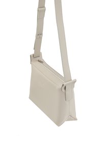 Borsa a tracolla color beige chiaro con finitura in pelle texturizzata, dotata di chiusura superiore con zip e tracolla regolabile. Design minimalista.