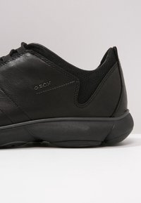 Sneaker neri con tomaia in pelle liscia e dettagli in rete. Presenta un design minimalista e una suola in gomma leggera per il comfort.