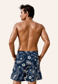 Costume da bagno blu navy con motivo floreale e paisley bianco, realizzato in materiale ad asciugatura rapida, con vita elasticizzata per il massimo comfort.