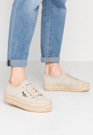 Baskets plateformes en toile beige avec semelles en jute tressée portées avec un jean bleu clair retroussé.