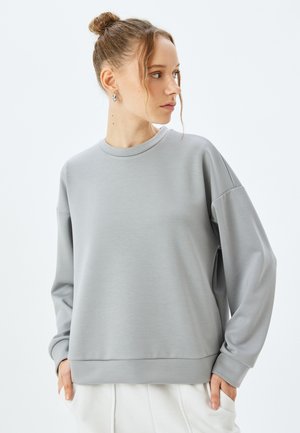 Szara bluza o luźnym kroju z okrągłym dekoltem, długimi rękawami i ściągaczami. Gładki, lekki materiał z delikatnym połyskiem.