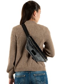 Bolso bandolera de cuero negro con cierre de cremallera, con una correa texturizada con la marca "vanessa". Se lleva cruzado en diagonal por la espalda.