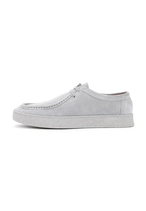 Chaussures en daim grises avec une forme arrondie, fermeture lacée et semelle en caoutchouc texturée. Coutures visibles qui soulignent les bords.
