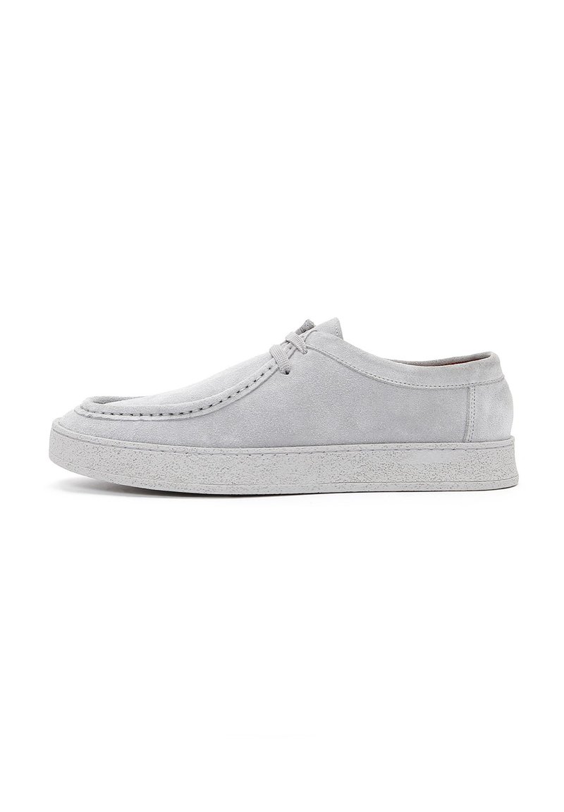 Zapatos de ante grises con forma redondeada, cierre con cordones y suela de goma texturizada. Costuras visibles a lo largo de los bordes.