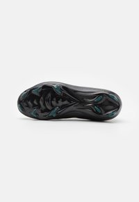 Black athletic shoe outsole featuring a textured surface, prominent studs, and teal accents, designed for traction and performance.