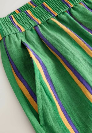Green fabric with elastic waistband featuring vertical purple and yellow stripes and a side pocket.