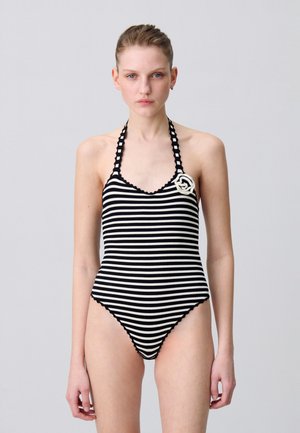 Costume da bagno a righe bianche e nere con spalline a halter e bordi ondulati. Presenta una rosa decorativa bianca sul lato sinistro.
