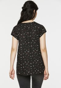 Blouse noire à manches courtes avec une coupe ample, arborant un motif abstrait multicolore, un empiècement froncé dans le dos et un ourlet arrondi.