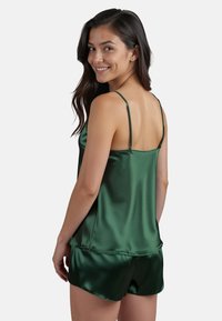Grünes Satin-Camisole- und Shorts-Set mit dünnen Trägern, glatter Textur und lockerer Passform. Die Shorts haben einen elastischen Bund.