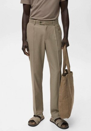 Beige maatpakken gemaakt van gladde stof met een rechte pijpdesign, voorzien van voorplooien en een knoopsluiting. Gecombineerd met een bruine tote bag.