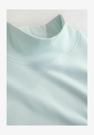 Cămașă albastru deschis, cu guler înalt, realizată dintr-un material moale. Are o textură netedă și cusături contrastante de-a lungul gâtului și umerilor.