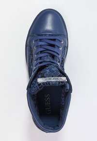 Granatowe sneakersy o błyszczącym wykończeniu, z teksturowanymi akcentami na sznurówkach, zaokrąglonym noskiem i metką na języku. Zapięcie na sznurówki.