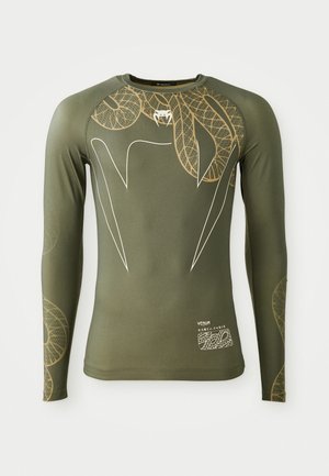 Long-sleeve athletic shirt in olive green with beige leaf patterns, featuring a round neck and fitted design. Text and logo on the lower side.