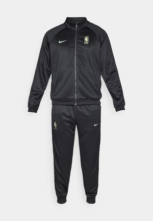 Crni Nike trenirac s jaknom na zatvarač s lažnom ovratnikom, elastičnim manžetama i odgovarajućim hlačama s džepovima. Uključene NBA logo zakrpe.