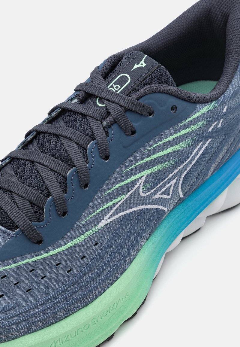 Szare buty sportowe z siateczkowego i syntetycznego materiału, z zielonymi akcentami i amortyzowaną podeszwą. Posiadają wyraźne sznurowanie i logo na języku.