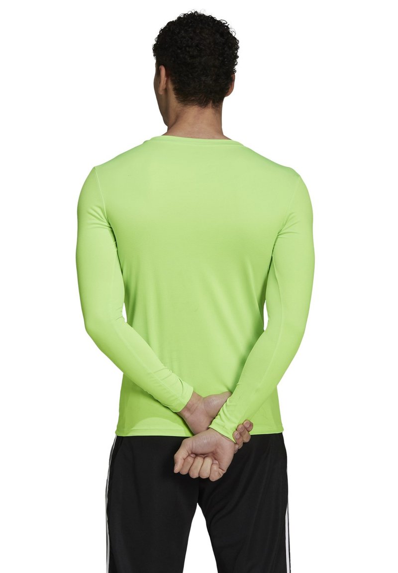 Neon green long-sleeve performance shirt with a crew neck, fitted design, and smooth texture, shown from the back. Black pants complement the shirt.