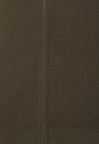 Stickad brun tröja med vertikal dragkedja i mitten, med en texturerad tygkvalitet och ribbade detaljer vid fåll och ärmar.