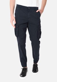 Pantaloni cargo navy con polsini elasticizzati, molteplici tasche laterali e chiusura con bottone. Realizzati in cotone resistente con una texture liscia.