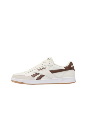 Witte en bruine Reebok lage sneaker met veters, logo op de zijkant en achterkant, en een witte zool met een gum buitenzool.
