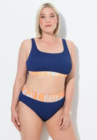 Navy-blaues Rippen-Bikini-Set mit einem orange- und hellblau gemusterten Bund. Das Oberteil hat einen quadratischen Ausschnitt, das Unterteil hat eine hochgeschnittene Passform.