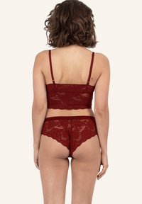 Rode kanten bralette met dunne bandjes en bijpassende kanten slipjes met bloemmotieven en geschulpte randen, die een doorschijnende textuur laten zien.