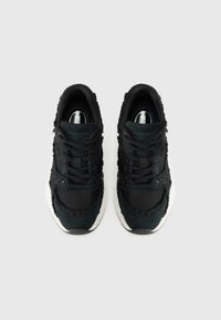 Schwarze sportliche Sneakers aus Mesh und strukturiertem Stoff, mit einer weißen Zwischensohle und schwarzen Schnürsenkeln. Subtile, abgenutzte Details im Obermaterial.
