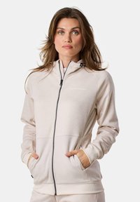 Light beige zip-up hoodie with a lined hood, front pockets, ribbed cuffs, and a subtle logo on the chest. Made of smooth, stretchy fabric.