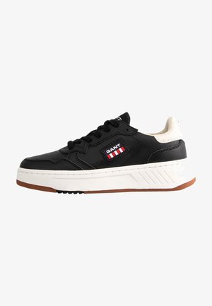 Black leather sneakers with a white and gum sole, featuring a GANT logo patch in red and white stripes, and textured accents on the sides.