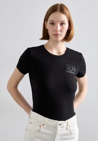 Mustat, istuvat t-paidat, joissa on lyhyet hihat, pyöreä kaula-aukko ja tekstuuri musta pä�ällyspalan, jossa on "EA7 EMPORIO ARMANI" -logo rinnassa.