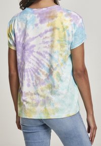 Kortærmet tie-dye t-shirt med pastelfarvede svømme i lilla, blå og gul på en hvid baggrund; blødt bommateriale.