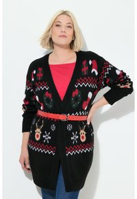 Schwarzer Strickcardigan mit Feiertagsmotiven, darunter Schneeflocken, Rentiere und Zuckerstangen, akzentuiert mit einem roten Gürtel, der in der Taille cinched.