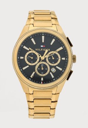 Montre-bracelet en métal doré avec cadran noir, trois sous-cadrans, affichage de la date à 4 heures, et index ainsi que aiguilles dorées.