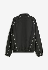 Jachetă neagră tip windbreaker cu manșete și tiv elastic. Prezintă dungi albe pe cusăturile umerilor și pe spate.