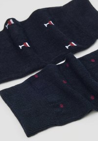 Granatowe skarpety z wzorem w kieliszki do wina w kolorze białym i czerwonym, z bordowymi kropkami. Teksturowana dzianina z prążkowanymi mankietami dla wygody.