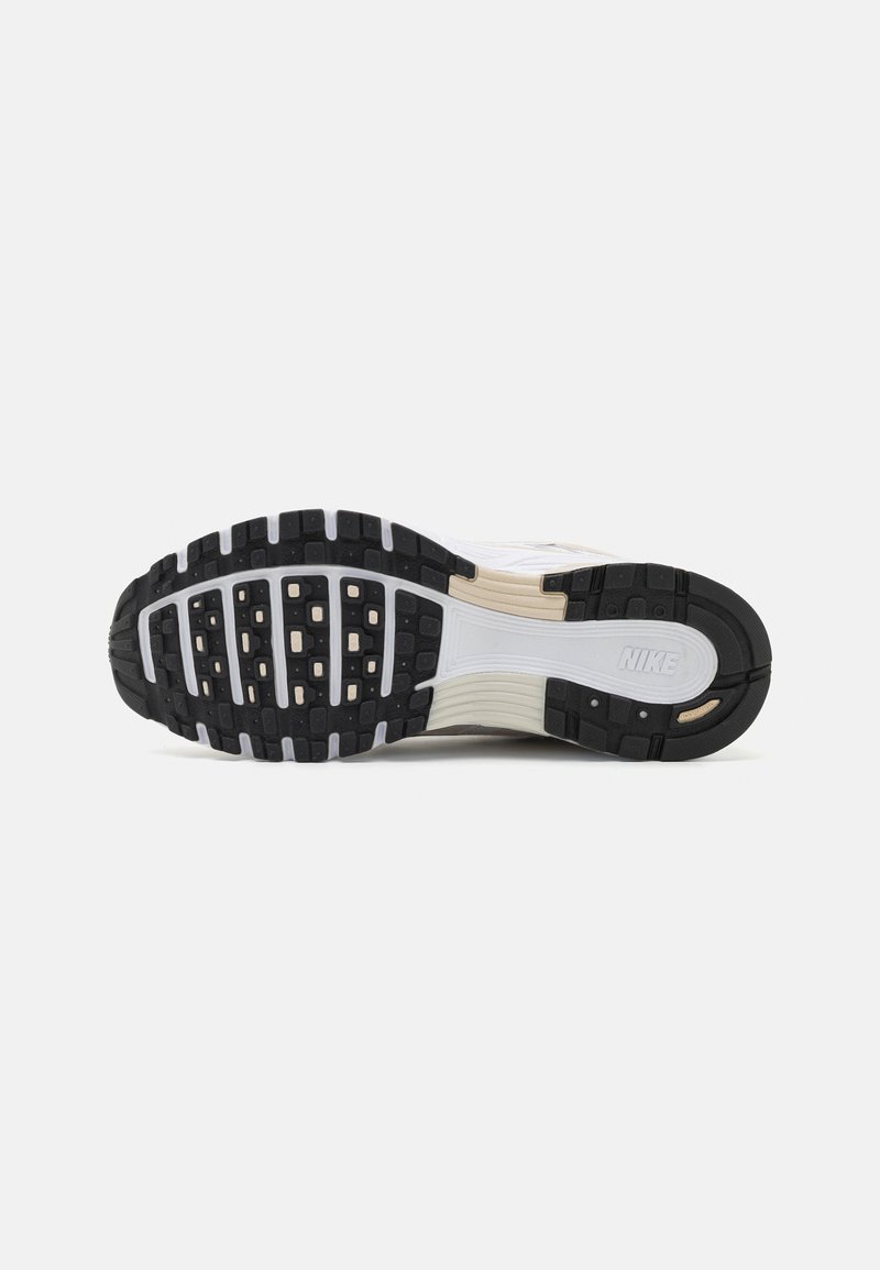 Nike-Schuhsohle mit einer schwarzen Gummiunterseite, die über strukturierte Rillen und weiße Akzente verfügt und ein geschichtetes Design für Traktion zeigt.