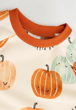 Chemise à manches longues présentant un fond crème avec des imprimés de citrouilles orange et bleu-vert. Le col est orange avec une texture lisse et une fermeture à pression.