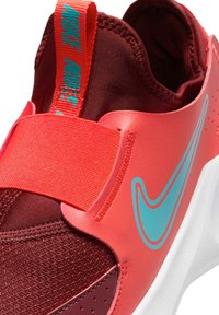 Zapatillas rojas y rosas con parte superior de malla texturizada, correa llamativa y logo turquesa. Diseñadas con un collar acolchado y suela blanca.