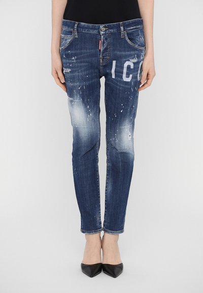Jeans skinny in denim blu scuro con dettagli strappati, leggera sbiaditura e lettere stampate bianche sul davanti. Abbinati a décolleté nere.