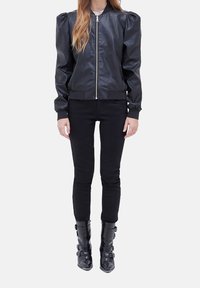 Svart läderbomberjacka med puffärmar, dragkedja fram, ribbade muddar och fåll, ihopparad med svarta skinny jeans och knähöga stövlar.