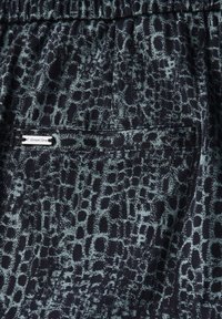 Tessuto nero con una trama di stampa animale in grigio, dotato di una cintura elastica e di un'etichetta piccola che indica il marchio, Street One.