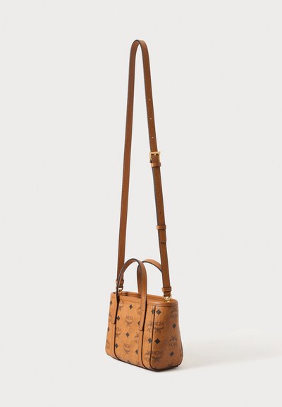 Petit sac bandoulière rectangulaire en cuir fauve avec une longue bandoulière réglable et un motif de logo noir partout.