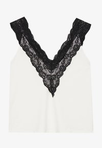 Top blanco sin mangas con un profundo escote en V y un ribete de encaje negro con bordes festoneados. Textura suave con un corte holgado.