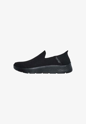 Zapatillas negras tipo slip-on con parte superior de punto, superficie texturizada y suela de goma ligera con un diseño de patrón para mayor tracción.