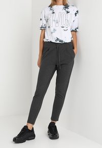 White and black marble-patterned t-shirt with large "LOVE" text, paired with dark gray tapered joggers and black sneakers.