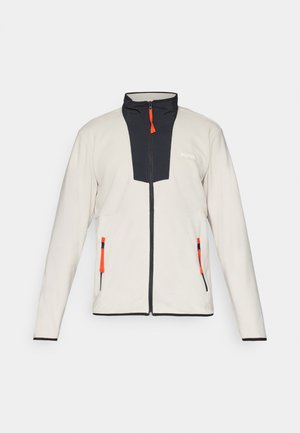 Világosszürke polárdzseki sötétkék elülső panellel, narancssárga cipzárhúzókkal és két cipzáras zsebbel. Magas gallérral és fekete részletekkel rendelkezik.